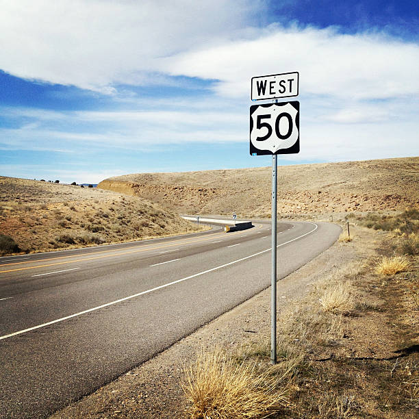 desert highway 50 west a state road bends through the rolling desert landscape.  square composition taken in western colorado.