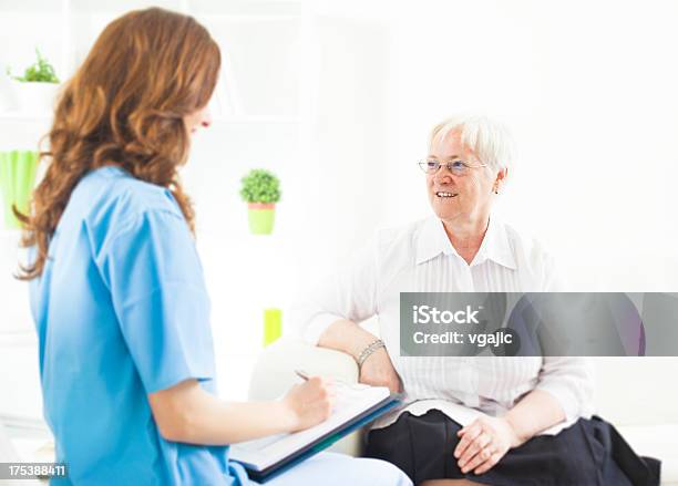 Doctor Tomando Notas De Mujer Senior Paciente Foto de stock y más banco de imágenes de Paciente - Paciente, Personal de enfermería, Entrevista - Acontecimiento