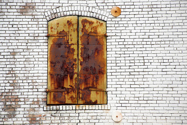 Old neglected rusty shutters closed on aging brick building.
