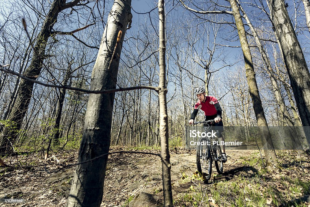 Mountain biking. Young man in the 20s mountain biking on a trail on a sunny spring day. Active Lifestyle Stock Photo
