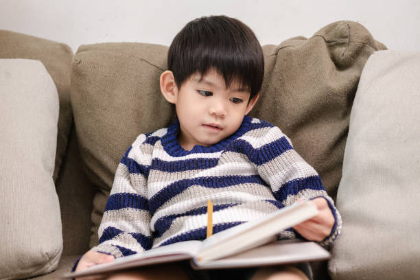 istock Asian boy reading a book on the sofa Learning outside the classroom 1753886652