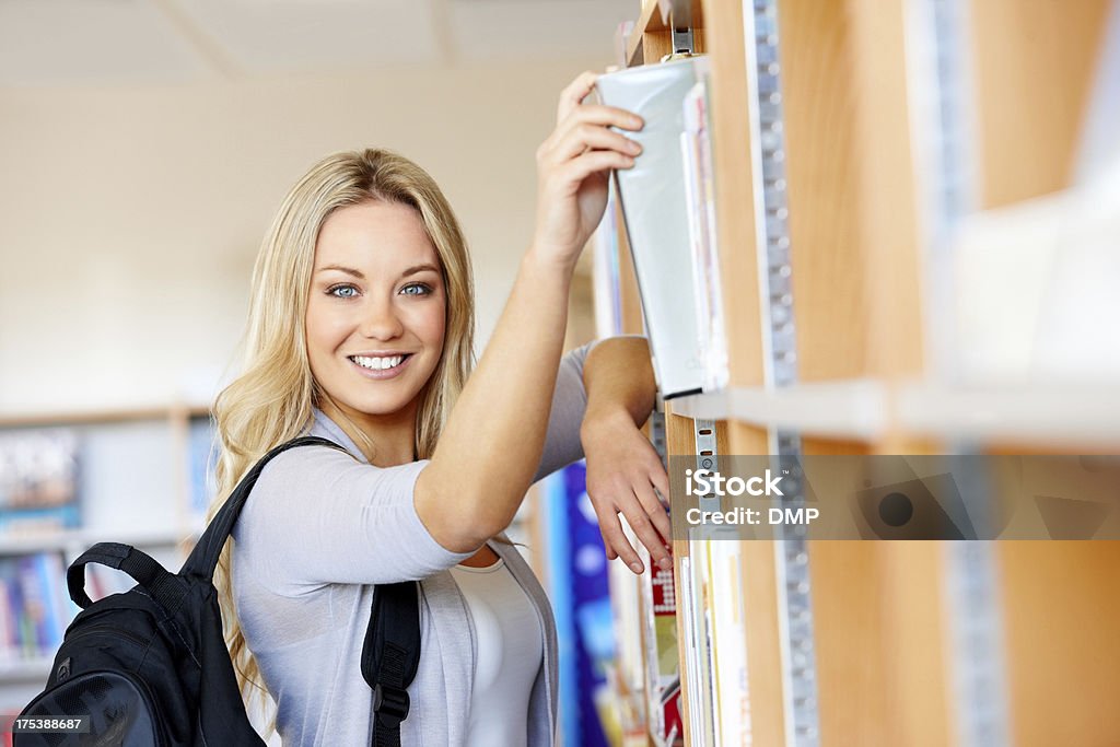 Muito jovem ESTUDANTE UNIVERSITÁRIO em uma biblioteca - Foto de stock de Bolsa - Objeto manufaturado royalty-free