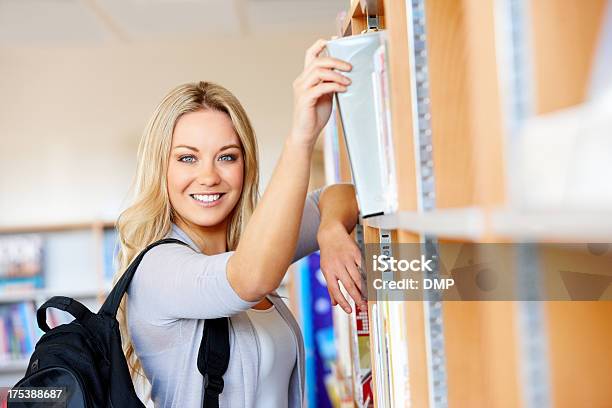 Foto de Muito Jovem Estudante Universitário Em Uma Biblioteca e mais fotos de stock de Bolsa - Objeto manufaturado