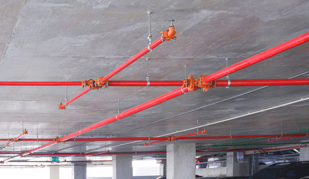 istock Red fire protection water pipeline system with sprinkler on concrete ceiling inside of parking garage building 1753887803