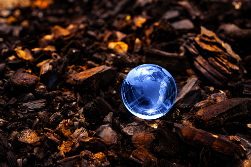 On a pile of burnt wood from the remains of an extinguished fire is a glass globe