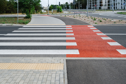 Pedestrian crossing with new white stripes on gray asphalt and marking for bicycle lane in city street at europe. Place to cross the road. Traffic rules concept