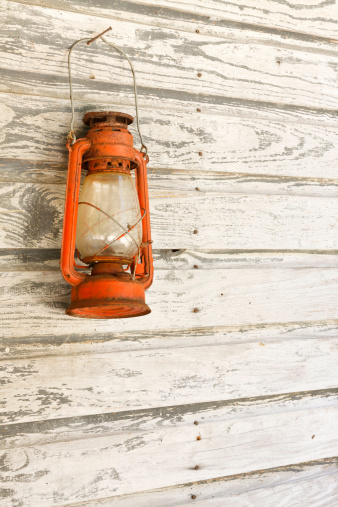 An antique lantern against side of rural wood farmhouse.