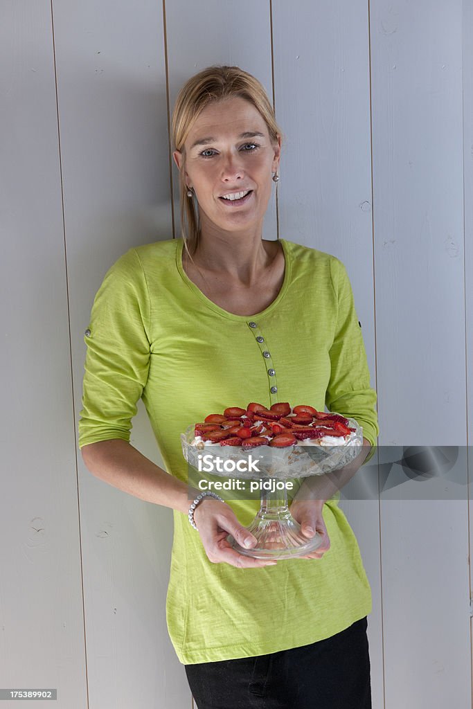 happy woman holding strawberry cheesecake smiling blond woman holding cakestand with strawberry cheesecake looking at the camera Cake Stock Photo