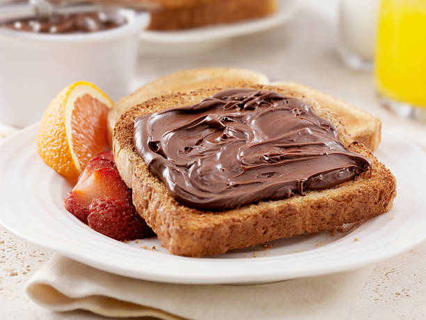 Chocolate Hazelnut Spread Chocolate Hazelnut Spread on Toast with Fresh Fruit- Photographed on Hasselblad H3D2-39mb Camera NUTELLA stock pictures, royalty-free photos & images