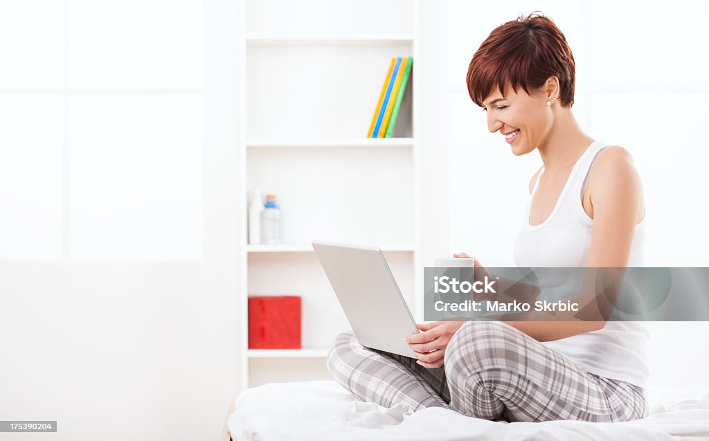 Chating en computadora portátil y sosteniendo una taza - Foto de stock de 20 a 29 años libre de derechos