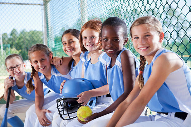 girls softball équipe assis dans le banc de touche - niveau junior photos et images de collection