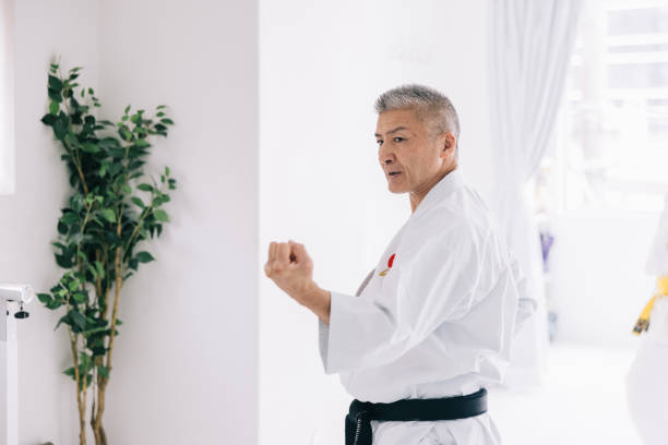 Japanese Karate sensei commands the attention of his Japanese students, demonstrating the art of kicking with grace and precision.