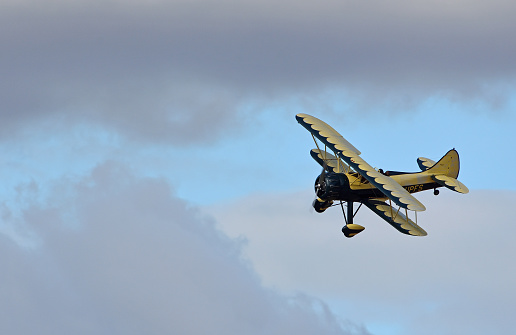 Little Gransden, Cambridgeshire, England - August 27, 2022: Vintage Waco UPF-7 biplane in flight againft clouds.