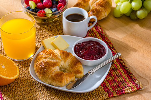 Croissant and jam breakfast. Coffee, orange juice and fruits