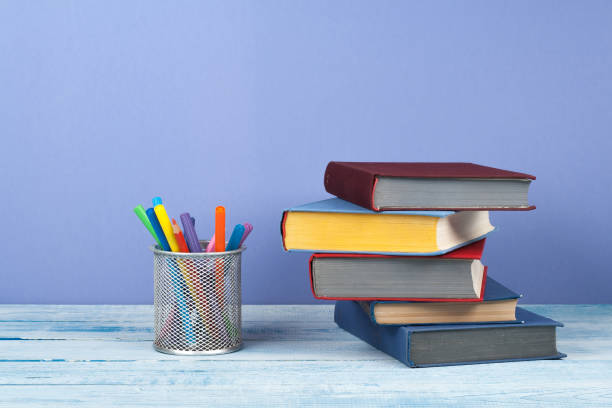 istock Book stacking. Open book, hardback books on wooden table and blue background. Back to school. Copy space for text. 1753949110