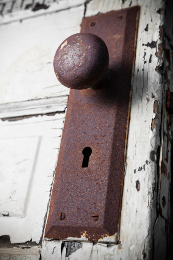 Old rusty door knob on worn door