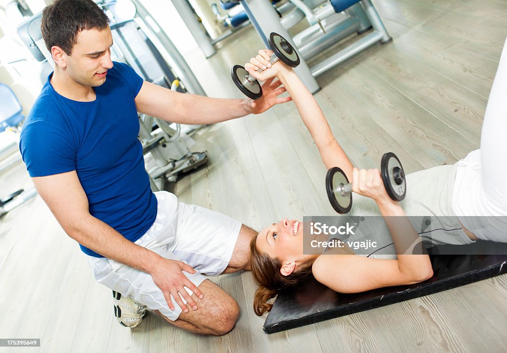 Mulher em uma academia de ginástica com personal trainer. - Foto de stock de 25-30 Anos royalty-free
