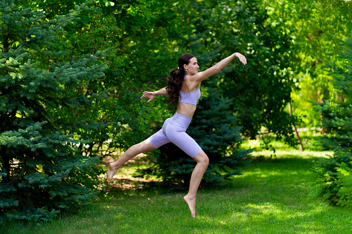 young fit woman jump in the air outdoors on a grass field