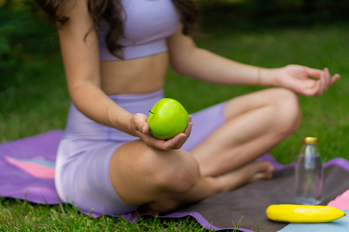 woman holding a fresh fruit during outdoors yoga class