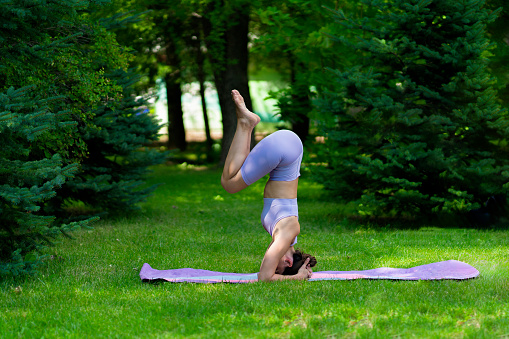 head stand yoga position on the grass field during summer day