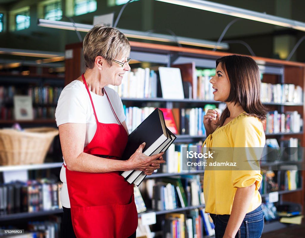 Bibliotecario di volontariato aiutando studenti - Foto stock royalty-free di Bibliotecario