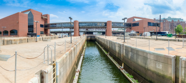 Panoramic view of the locks on the Charles River Dam. The Massachusetts State Police Marine Unit occupies red brick buildings on either side of the dam with a skywalk for easier access from one to the other.