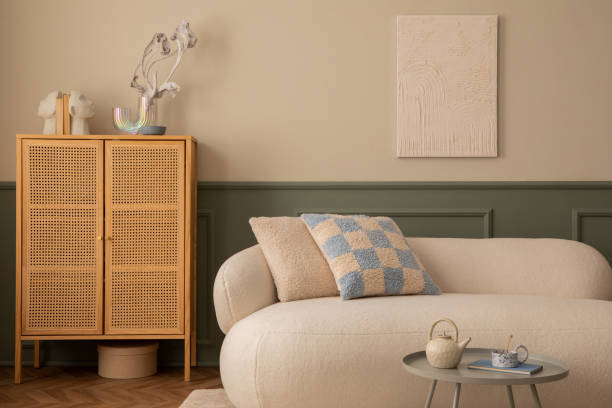 istock Creative composition of living room interior with mock up poster frame, beige sofa, white pouf, patterned pillow, rattan sideboard, white pouf, plaid and personal accessories. Home decor. Template. 1753965867
