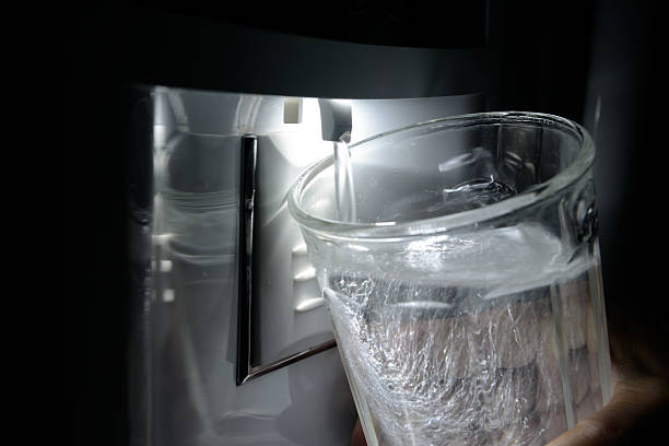 Glass Being Filled at Refrigerator Water Dispenser stock photo