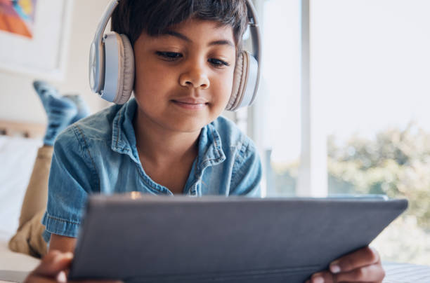 ragazzo bambino, tablet e cuffie sul letto, lettura o idea con e apprendimento, film e relax con video web. bambino maschio, touchscreen digitale e pensiero in camera da letto per audio, spettacolo e streaming a casa - one little boy audio foto e immagini stock