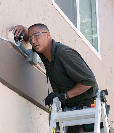 A technician adjusting a security camera while installing the system to the exterior of a building.