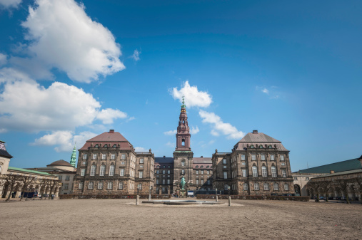 The Riding Ground Complex and fountain in the central courtyard of Christiansborg Palace, the historic castle on Slotsholmen, home of the Folketing - Danish parliament - the Prime Minister's Office and Danish Supreme Court under blue spring skies in the heart of Copenhagen, Denmark. ProPhoto RGB profile for maximum color fidelity and gamut.