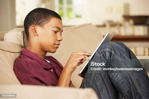 Teenage Boy Sitting On Sofa At Home Stock Photo - Download Image Now - Digital Tablet, Teenager, Teenage Boys