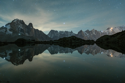 Starry Sky over Mountains and Reflection in Lac Blanc Lake. Night Landscape. Aiguilles Rouges, French Alps, France.