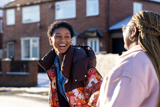 Over-the-shoulder shot of two young adult friends walking together through a residential street. They are talking, smiling and laughing together. They are located in Newcastle Upon Tyne

Video also available of this scenario.