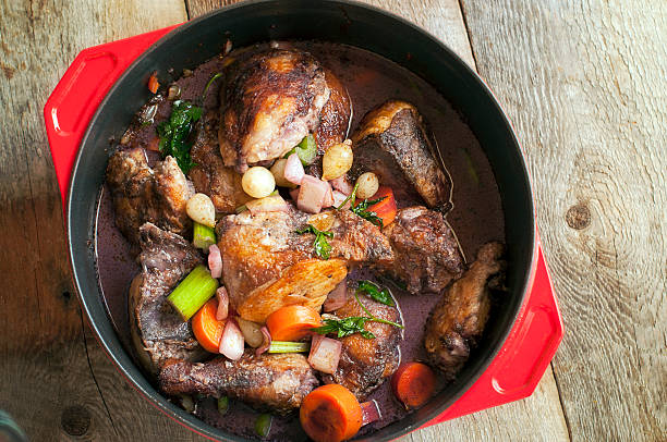French Coq au vin in pot sitting on wood table stock photo