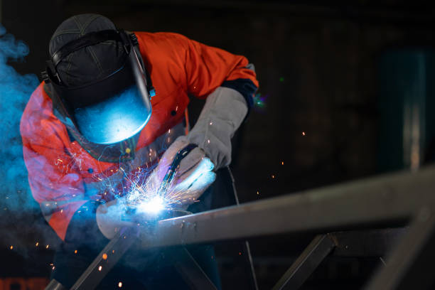 istock Engineer in protective suit expertly welds steel, creating a mesmerizing display of sparks that seem to dance and spread like a beautiful spectacle. Professional is contributing to the manufacturing process, adding value and strength to steel components. 1754002998