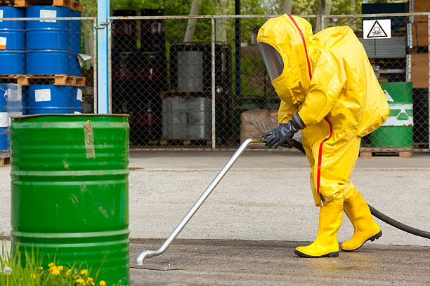 Worker in yellow hazmat suit cleaning ground
