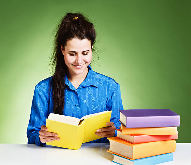 istock Smiling woman with many books looks down, reading 175401198
