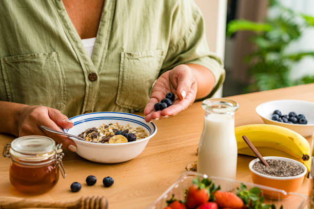 istock Woman adding berries to a bowl preparing healthy meal 1754015225
