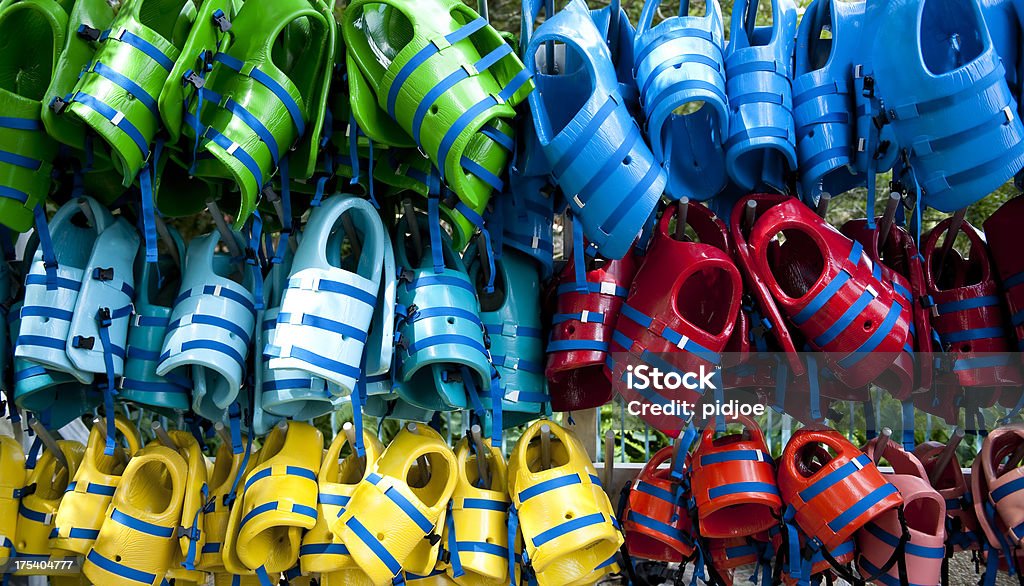 colorful life jackets hanging on rack "close up on rack with green, blue, yellow and red life jackets" Aquatic Sport Stock Photo