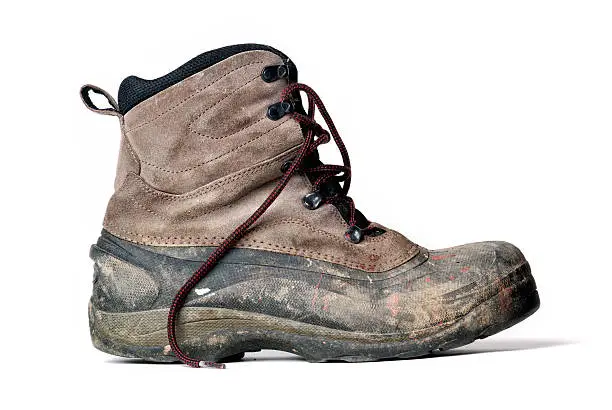 Side view of an unlaced and dirty work boot isolated on a white background