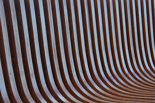 Wooden brown curved slats. Element of a bench, exterior decoration with texture. Abstract background.