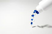 Blue and White Pills Pouring out of a Bottle