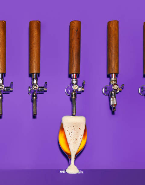 birra dorata che versa dalla spina in un bicchiere ghiacciato. la birra si forma densa, schiumosa e trabocca. - vertical studio shot indoors pink foto e immagini stock