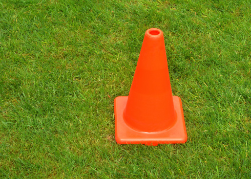 Close up of an Orange Traffic Cone on grass.  See also