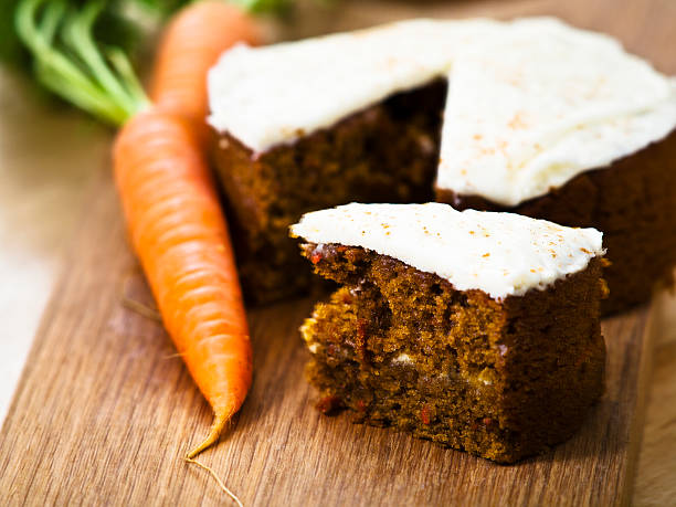 Carrot cake with a carrot on the side Close-up of pecanut Carrot Cake with carrot on service board.more dessert photos: carrot cake stock pictures, royalty-free photos & images