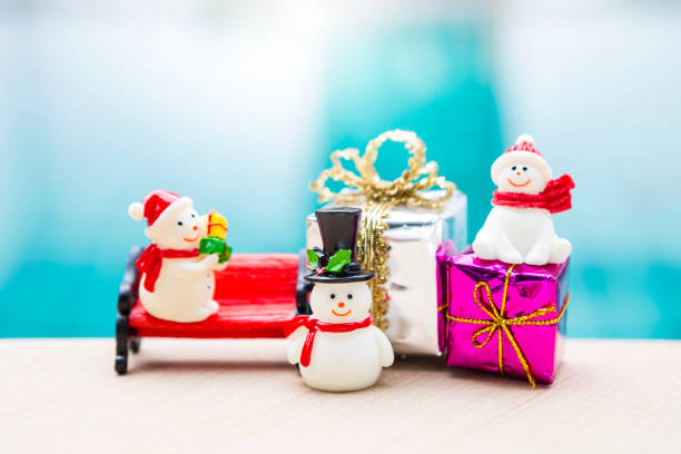 istock Snowman doll collections with gift box over blurred blue water background 1754079705