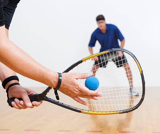 Racquetball Two men playing racquetball on court. One serving. squash stock pictures, royalty-free photos & images