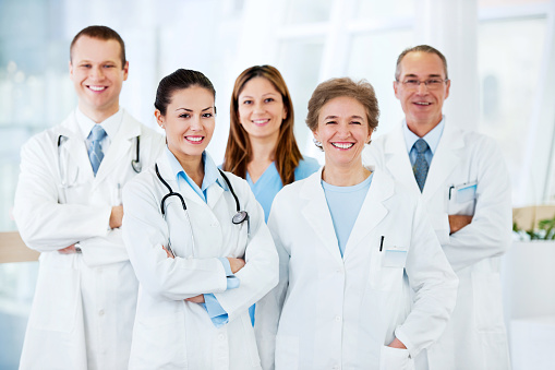 Group of cheerful doctors standing together and looking at camera.
