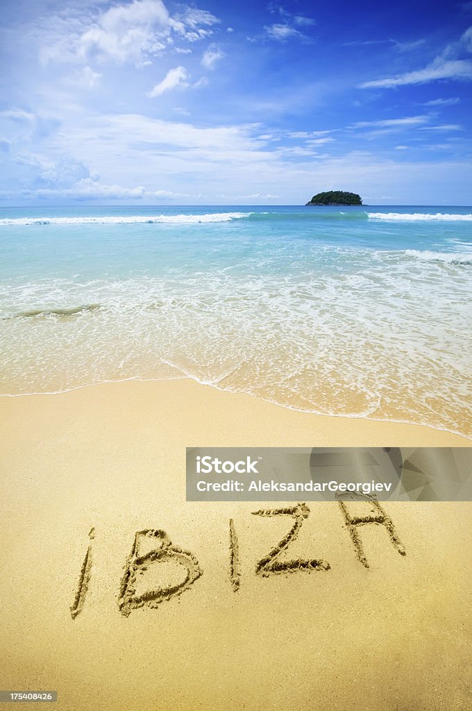 Ibiza written in the sand of a tropical beach "Ibiza written on the sand of a beautiful tropical beach. Visible are one island in the sea, turquoise water, little splashy waves, golden sand and beautiful cloudscape over the sea.See more images like this in:" Ibiza Island Stock Photo